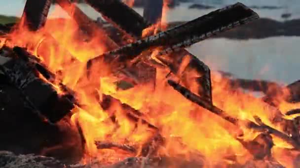 Inget ljud. Närbild video av ett brinnande picknickbord i slutet av en fest av en vattenförekomst. Sommarlov kul eller skadlig förstörelse av egendom. Rasande Dans flammor, intensiv värme och rök. — Stockvideo