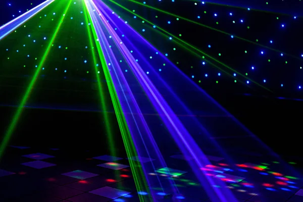 Helle Nachtclub-Laserlichter, die sich durch den Rauch der Rauchmaschine schneiden und Licht und Regenbogenmuster auf der Tanzfläche erzeugen. Laserlichter mit Bokeh im Hintergrund. Inspiration für Mardi Gras oder Nightlcub Promotions. Stockbild