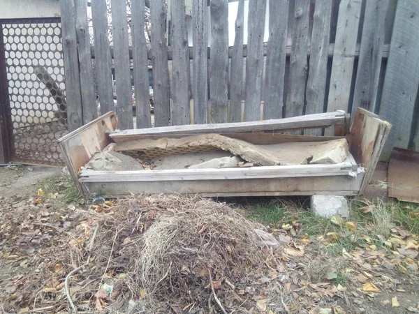 Photo of an old sofa, which collapsed from old age and stands on the street in the open air.