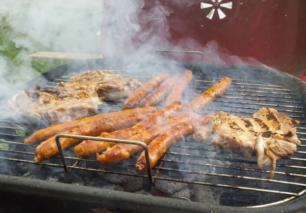 Variety of meat on an outdoor, sunlit, smoking barbecue grill