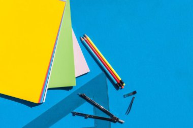 Geometri yaprak renkli kağıtlar, pusula, cetveller ve kalem ile mavi arka plan - üstten görünüm ayarla
