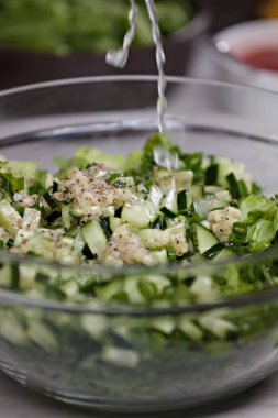 Limon suyu besleyici bir yeşil salata salatalık, fındık ve taze soğan cam kapta ile üzerinde sıçrama yakın çekim