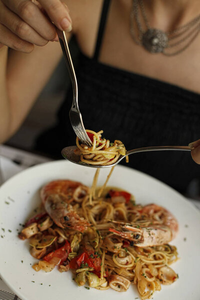 Woman eating seafood pasta with king prawns, shrimps and squids
