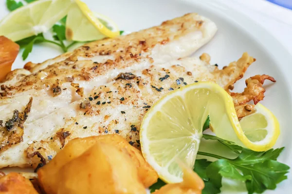 Fried white fish fillet garnished with roasted potatoes, lemon slices and parsley, Lebanese cuisine