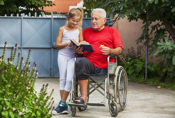 8 year old happy granddaughter helping her disabled grandfather outside reading