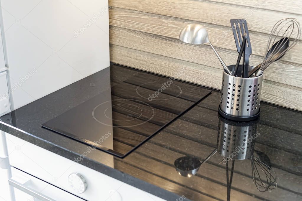 Close-up of a modern kitchen, a reflection of kitchen cutlery on the granite working surface - kitchen appliances, glass top stove