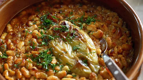 Serbian National Cuisine dish Baked Beans or Prebranac served with green paprika and parsley in a terracotta pot
