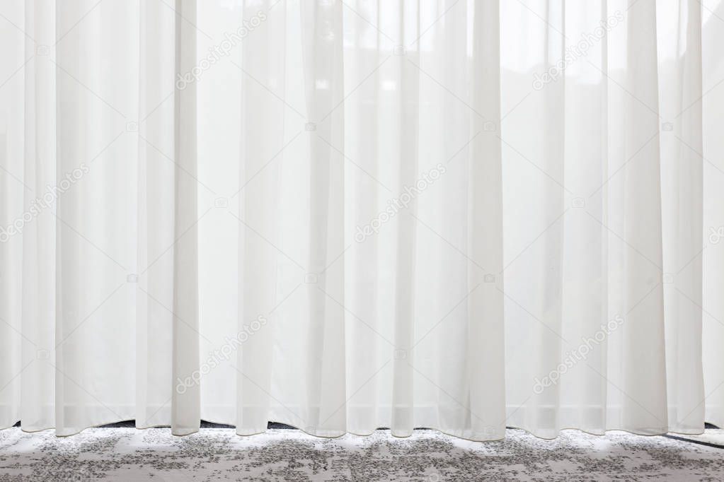 Long, white, semy see-through curtain hanging in the window