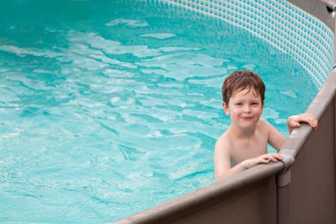 Yüzme havuzunda oynayan mutlu çocuk. Yaz günü dışarıdaki su havuzunda eğleniyorum. Tatillerde boş vakit ve yüzme. Mutluluk ve neşe.