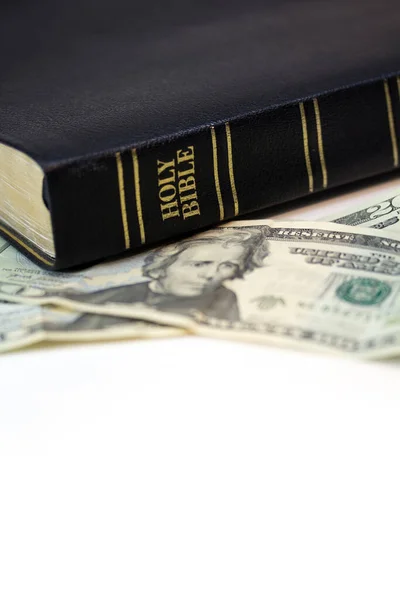 A holy Christian bible with a twenty dollar bill isolated on a white background.