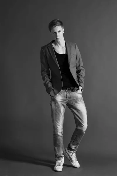 Young man in black t-shirt and stylish blazer posing on grey background