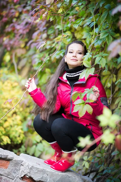 Młoda Wesoła Kobieta Czerwonym Płaszczu Stwarzające Zielonych Liści — Zdjęcie stockowe