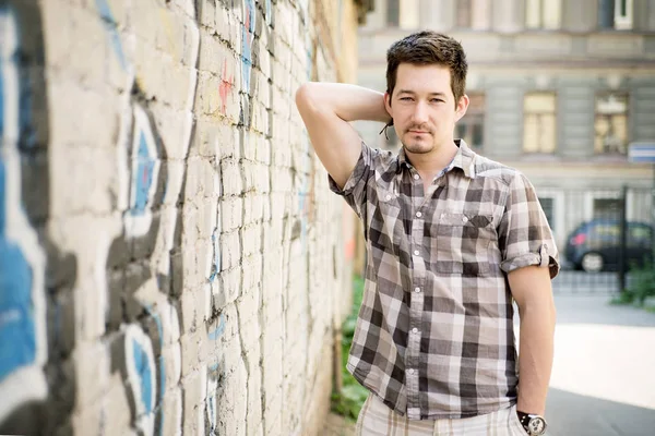 Young man in casual outfit posing on city street