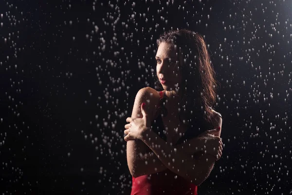 Portrait of young sensual woman in slim red dress posing under water drops