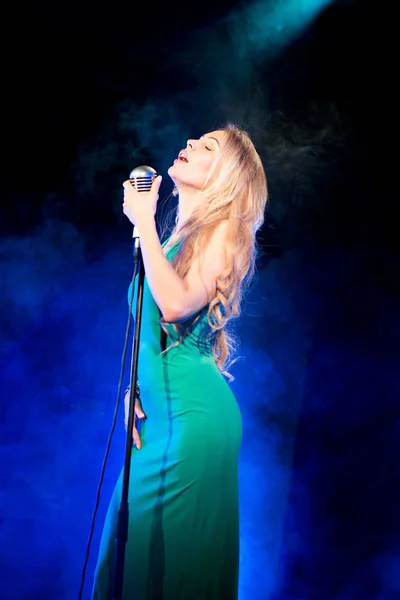 ステージで歌っているエメラルドのドレスでゴージャスな金髪女性 — ストック写真