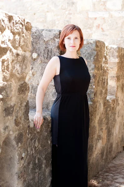 Kobieta Czarnej Sukience Kamieniu Tle Muru — Zdjęcie stockowe