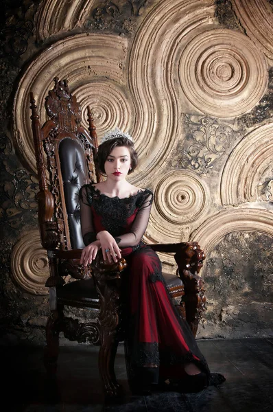 Queen in red dress sitting on throne. Symbol of power