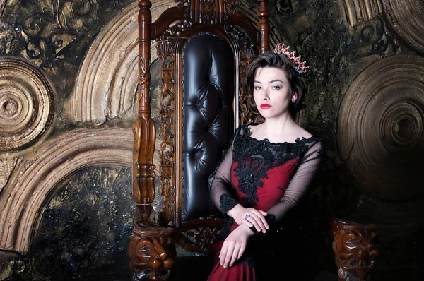 Queen in red dress sitting on throne. Symbol of power