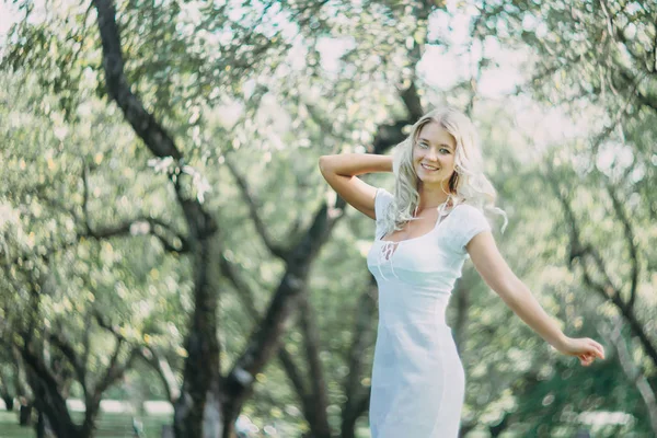 快乐的金发女郎在白色的夏装散步在公园 — 图库照片