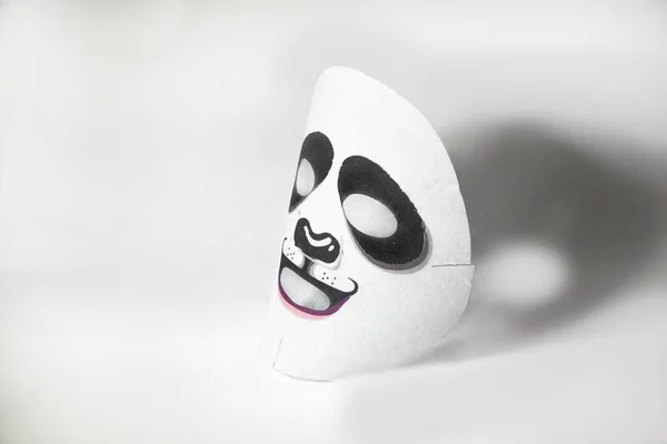 Tissue mask for the face with a panda pattern. On a white background. Moisturizing face is nice and fun.