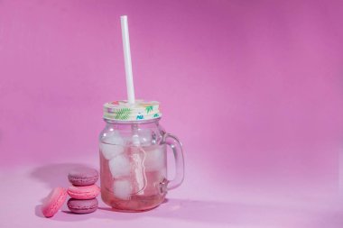 Renkli bir arka plan üzerinde Macaroons, renkli Fransız macarons kurabiye görüntü. Pembe bir arka plan üzerinde Macaron fransız pasta, minimal kavram. Bir sürü makaron. Cam bir kabın içinde buzlu ahududu limonata. Pipetle. Ferahlatıcı içecek.