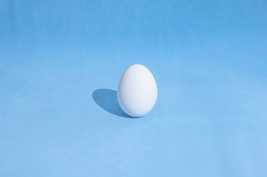 Mavi bir zemin üzerinde beyaz Paskalya yumurtalarından yapılmış gıda arka plan. Tasarım, görsel sanatlar, minimalizm, üst görünüm, düz yatıyordu, sert ışık, sert gölgeler.