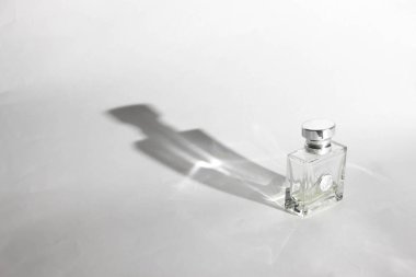 Beyaz arka planda parfüm şişesi. Beyaz siklorama. Uzun gölge, sert ışık ve sert gölge ile. 