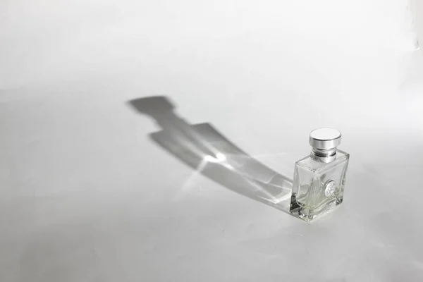 Perfume bottle on a white background. White cyclorama. With long shadow, with hard light and hard shadow.