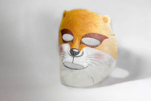 Tissue mask for the face with a pattern of a fox or a cat. On a white background with a shadow. Moisturizing face is nice and fun.