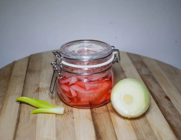 White onions, pickled in brine of pink vinegar with salt. Marinated onions can be stored in a glass jar. Against the background of the portion of white onion bulbs.
