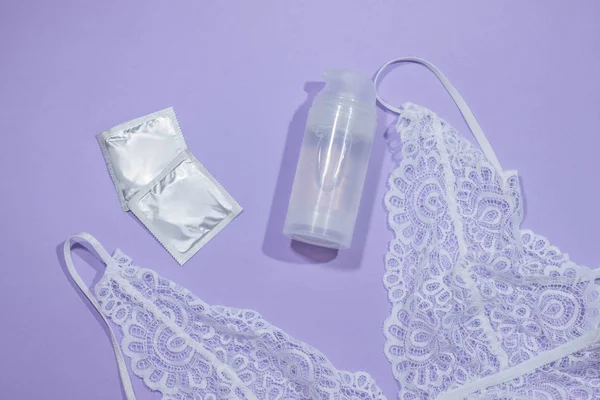 Samimi bir kayganlaştırıcı ve pastel arka planda dişi bir sütyen. Prezervatif. Özel jel. Rahat seks, korunan seks..