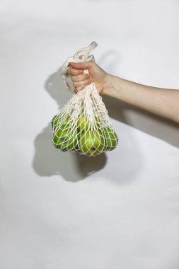 Beyaz bir arka planda, kadın ellerinde bir sicim torbasında elmalar. Konsept plastik değil. Çevresel bir ürün seçin.  