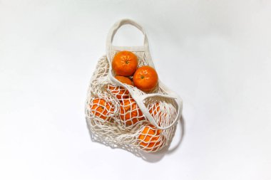 Sicim torbasında taze mandalinalar, arka planda çevre dostu ürünler. Plastik yok, sadece doğal malzemeler ve doğal ürünler. Plastiksiz yaşam kavramı.