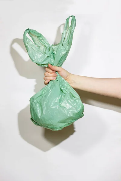 Beyaz bir arka planda, kadınların ellerinde yeşil plastik torba. Konsept plastik değil. Çevresel bir ürün seçin. 