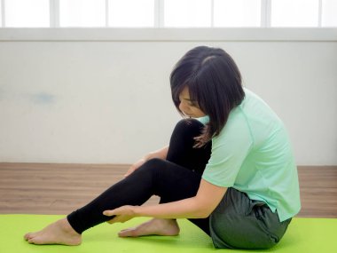 Spor giyimli genç ve güzel bir kadın esneme hareketleri yapıyor.