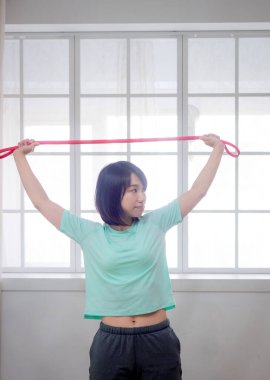 Genç kız spor bandıyla aerobik egzersizi yapıyor.