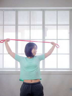 Genç kız spor bandıyla aerobik egzersizi yapıyor.