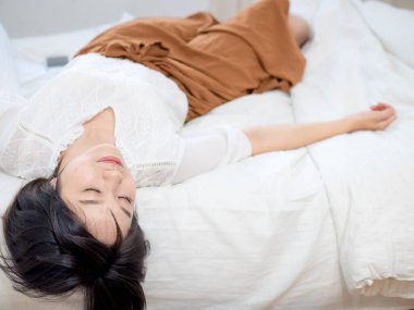 Genç bayan yatakta uzanmış dinleniyor.