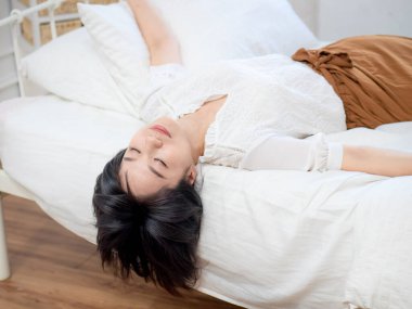 Genç bayan yatakta uzanmış dinleniyor.