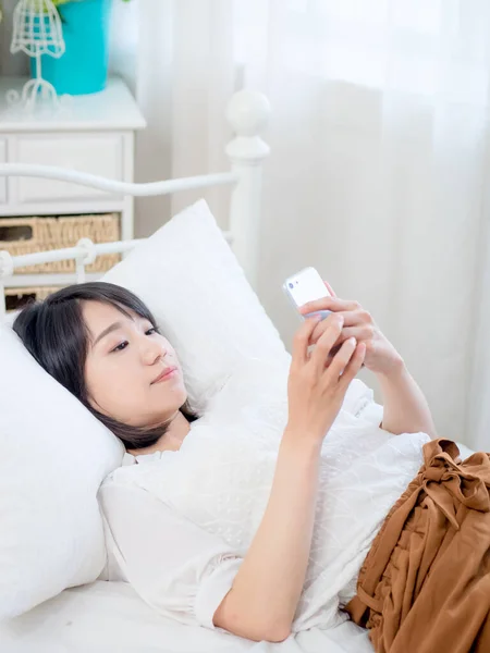 asian girl on bed checking smartphone