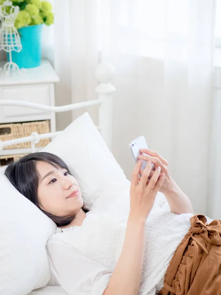 asian girl on bed checking smartphone