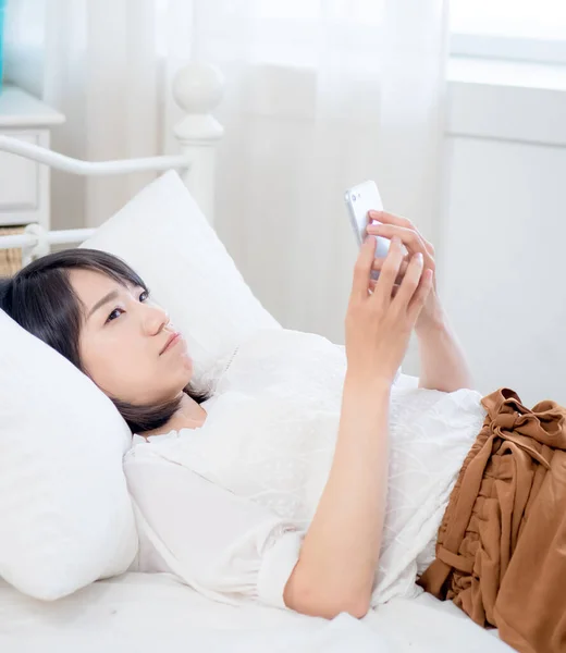asian girl on bed checking smartphone