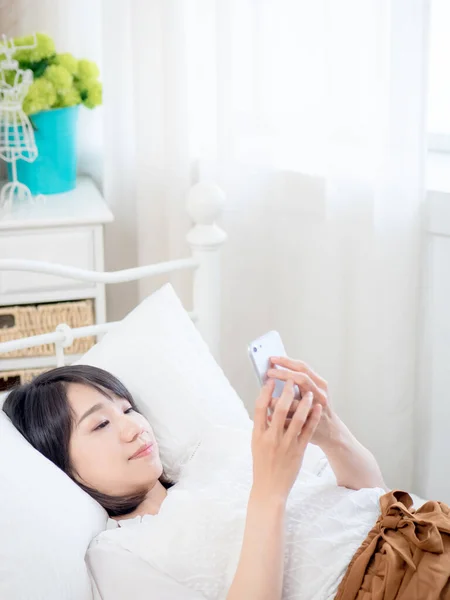 asian girl on bed checking smartphone