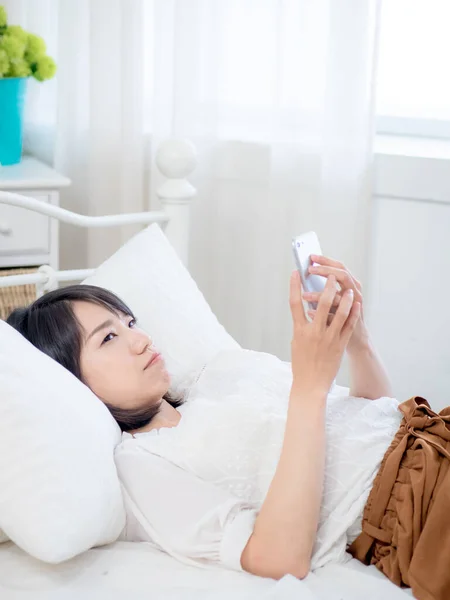 asian girl on bed checking smartphone