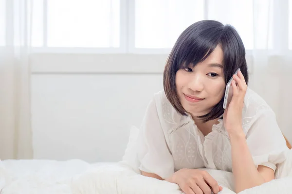 一个美丽的年轻亚洲女人的画像 她用手机聊天 躺在房间的床上 与年轻女孩的生活方式和放松时间概念 — 图库照片