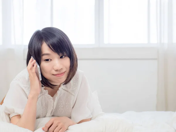 Evdeki Bir Odanın Yatağında Cep Telefonuyla Konuşan Güzel Asyalı Bir — Stok fotoğraf