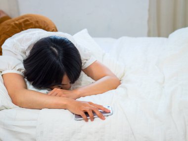 Genç bayan yorgun ve cep telefonuyla uyuyor.