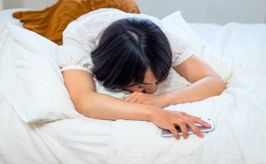 Genç bayan yorgun ve cep telefonuyla uyuyor.