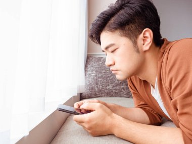 Gündelik kıyafetler giyen ve akıllı telefon kullanan genç bir adam.