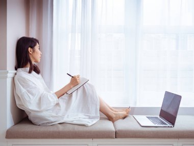 Güzel bir Asyalı kadın bir kitaba bir şeyler yazar.